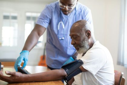 Healthcare worker checking a patient's blood pressure; illustrative stock image, not a named provider or employee.